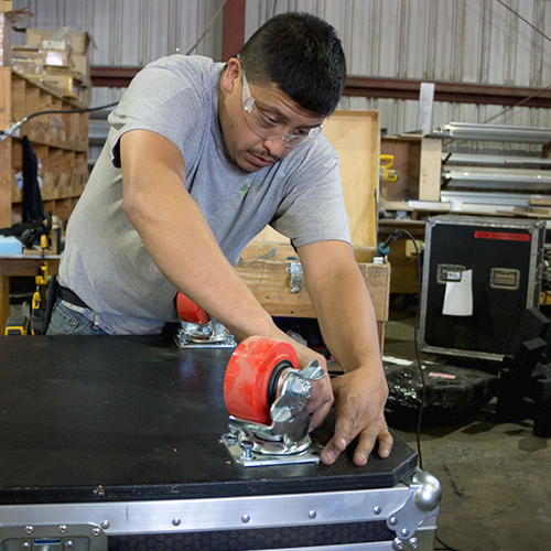 Caster wheels being added to a large custom made ATA case by a Larson Packaging Team member