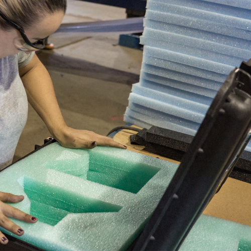 Custom foam insert being placed into a Pelican case by LPC team member